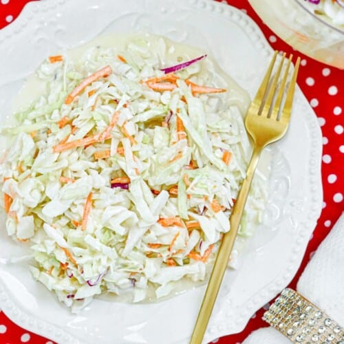 A white plat filled with homemade coleslaw. A gold silver place in the plate.