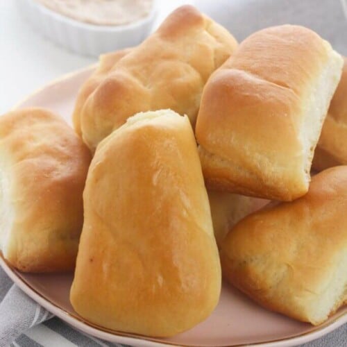 Golden brown Texas Roadhouse rolls served on a pink plate.