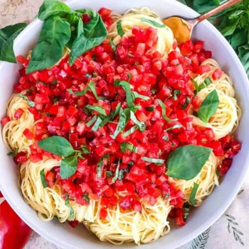 Copycat Olive Garden Capellini Pomodoro served in a white bowl and topped with fresh chopped basil.