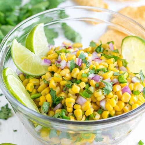 Copycat Chipotle Corn Salsa in a glass bowl, garnished with lime pieces.
