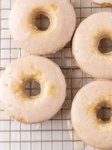 4 glazed vegan donuts on a wiring rack - feature