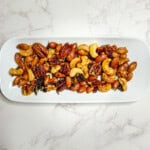 rosemary and thyme spiced nuts on a white saucer plate