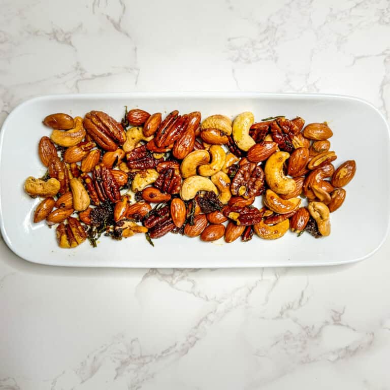 rosemary and thyme spiced nuts on a white saucer plate