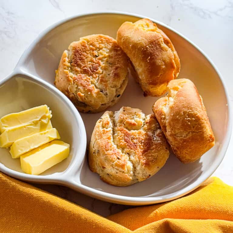 air fryer frozen biscuits served on a white plate with slices of butter on the side
