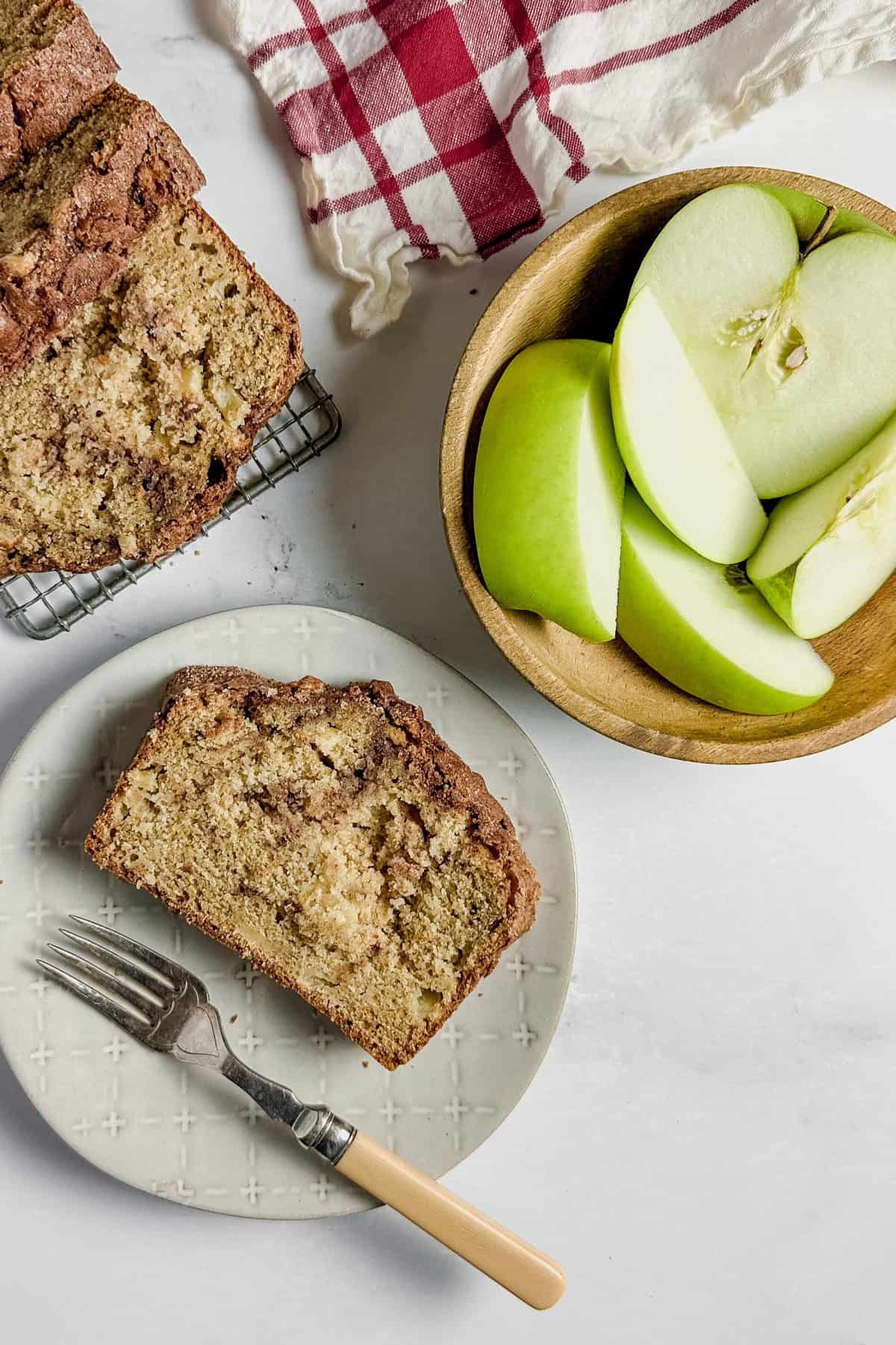 Cinnamon-Apple-Bread-slide-on-a-plate-with-a-side-of-apples-and-baked-loaf-on-the-side