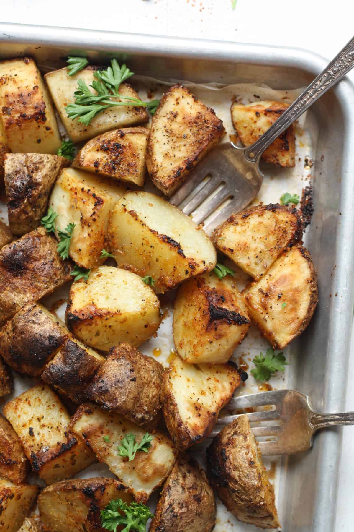 Close-up image of roasted potatoes digging into potato cubes with a fork