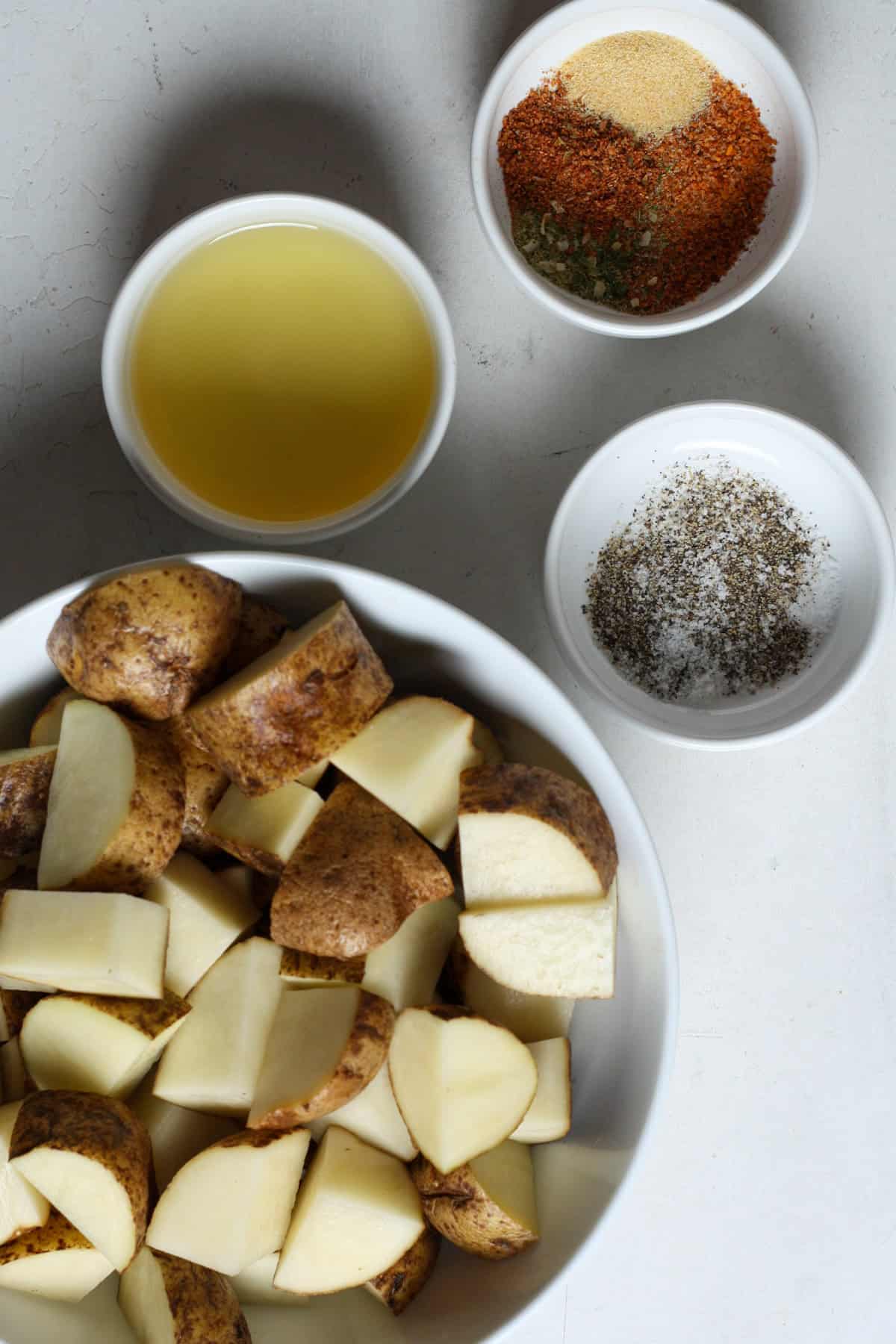 Ingredients for making roasted seasoned potatoes - oil, spices, potatoes