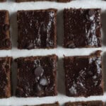 vegan black bean brownies - cut into squares on a parchment paper with chocolate chips on top