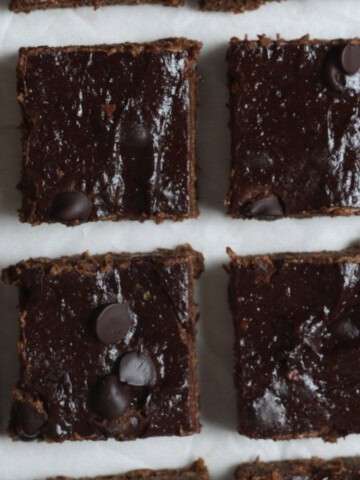 vegan black bean brownies - cut into squares on a parchment paper with chocolate chips on top