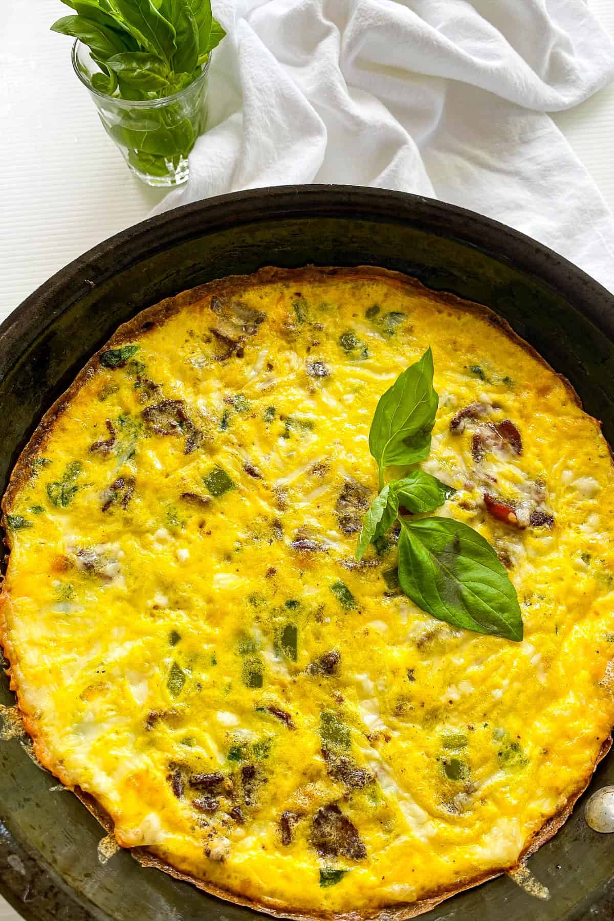 Veggie loaded Frittata in a pan overhead shot with basil garnish 