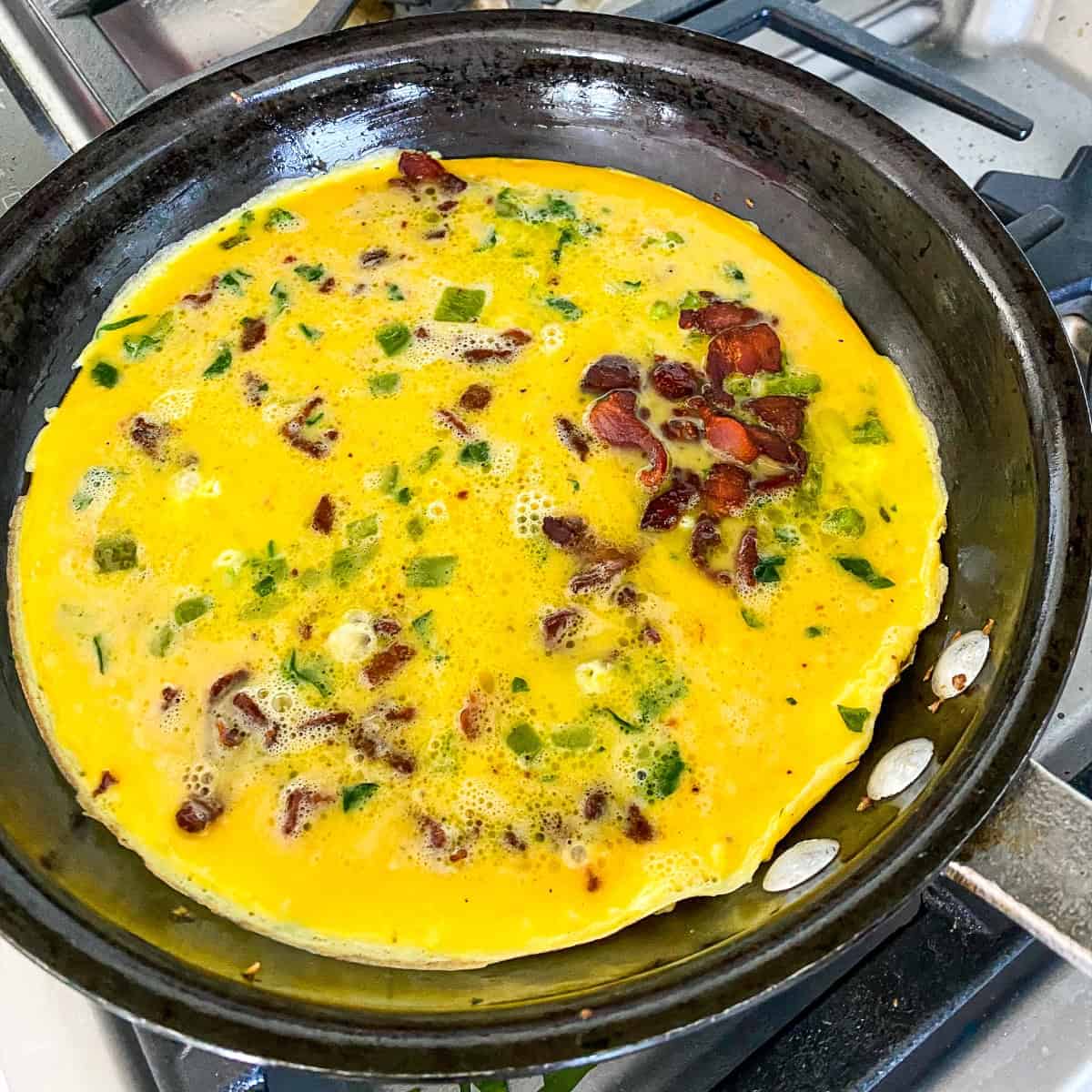 Add bacon and cheese to the egg and vegetable frittata mix.
