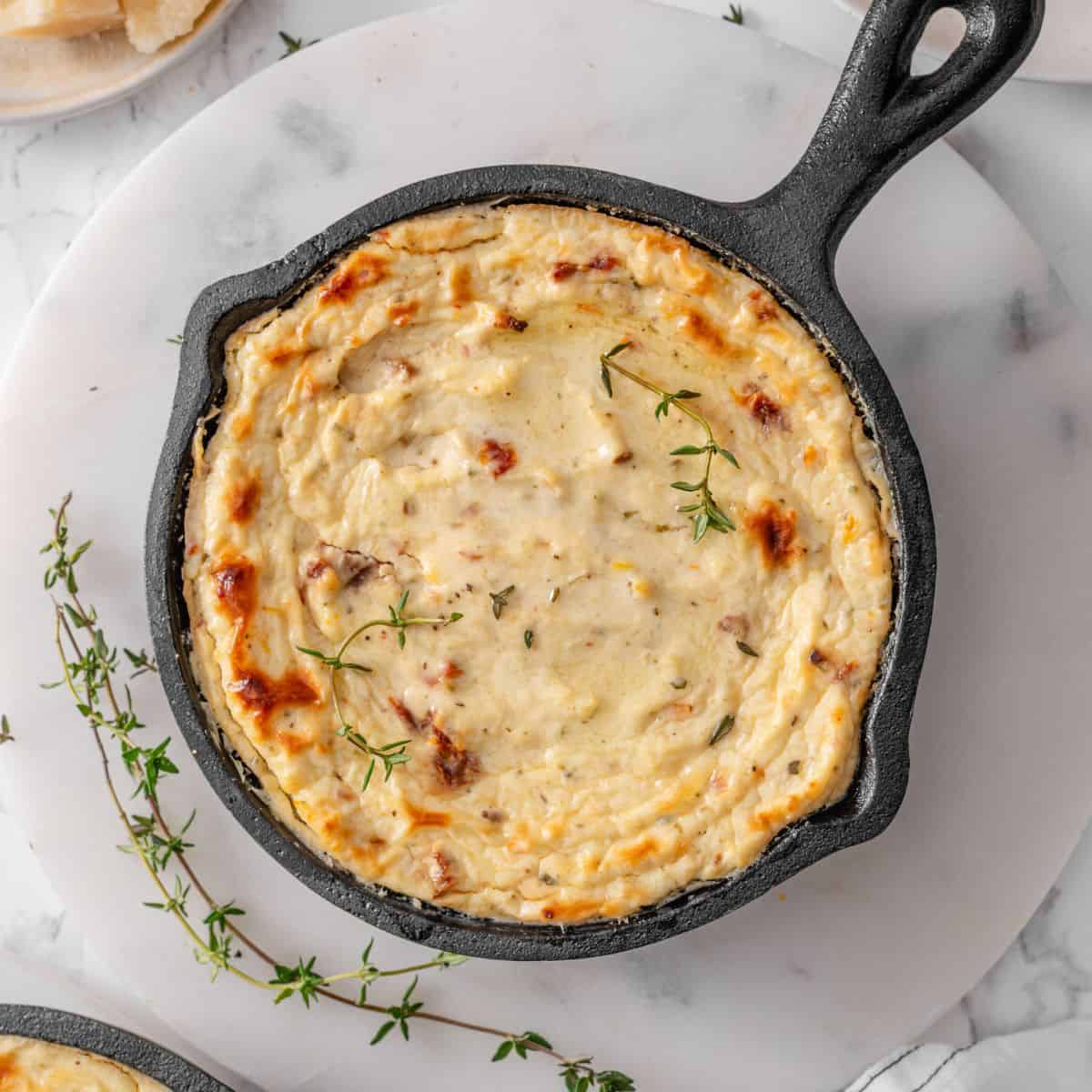 Ricotta dip baked in cast iron pan, served with fresh herbs