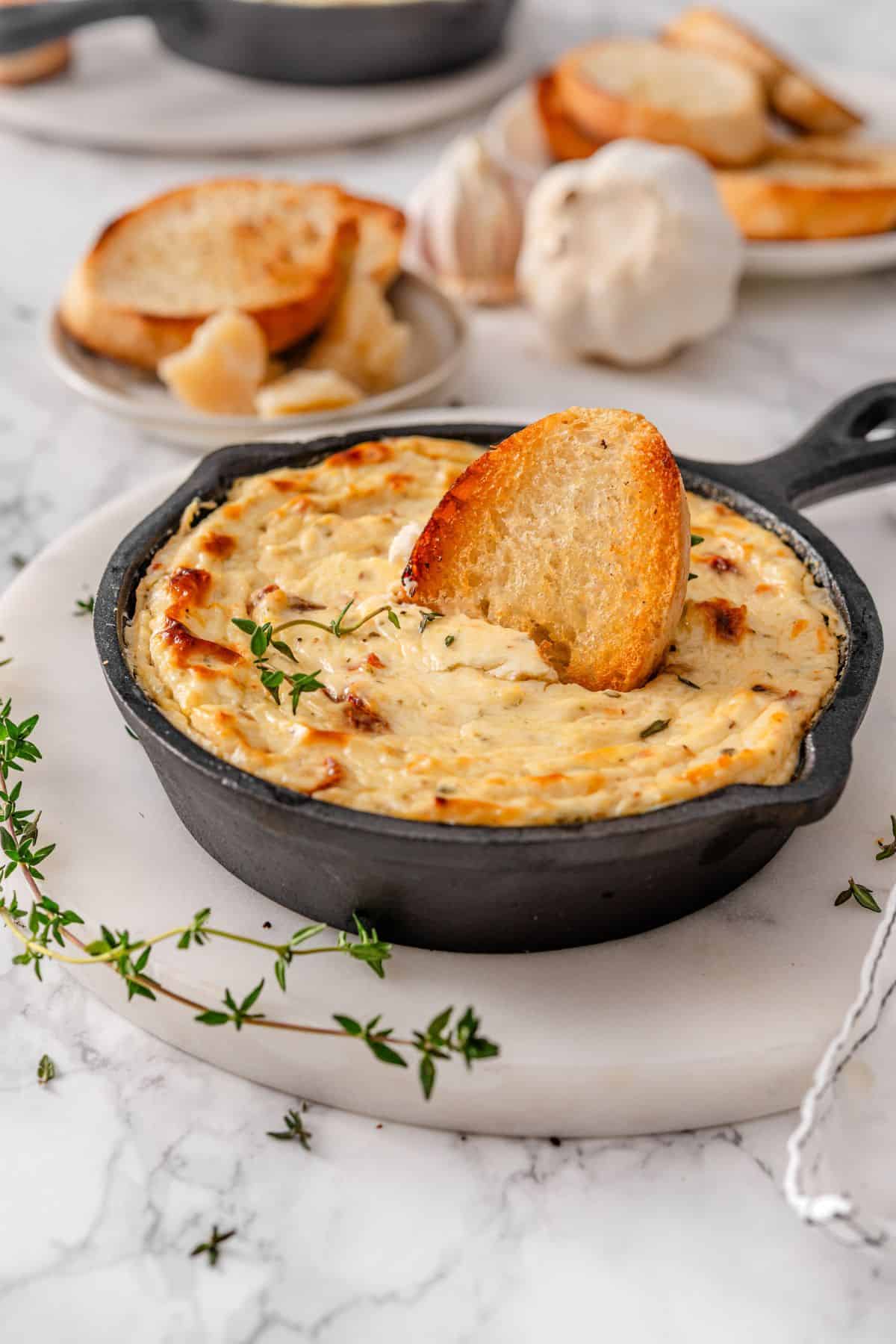 oven baked ricotta dip with toasted baguette dipping into the middle