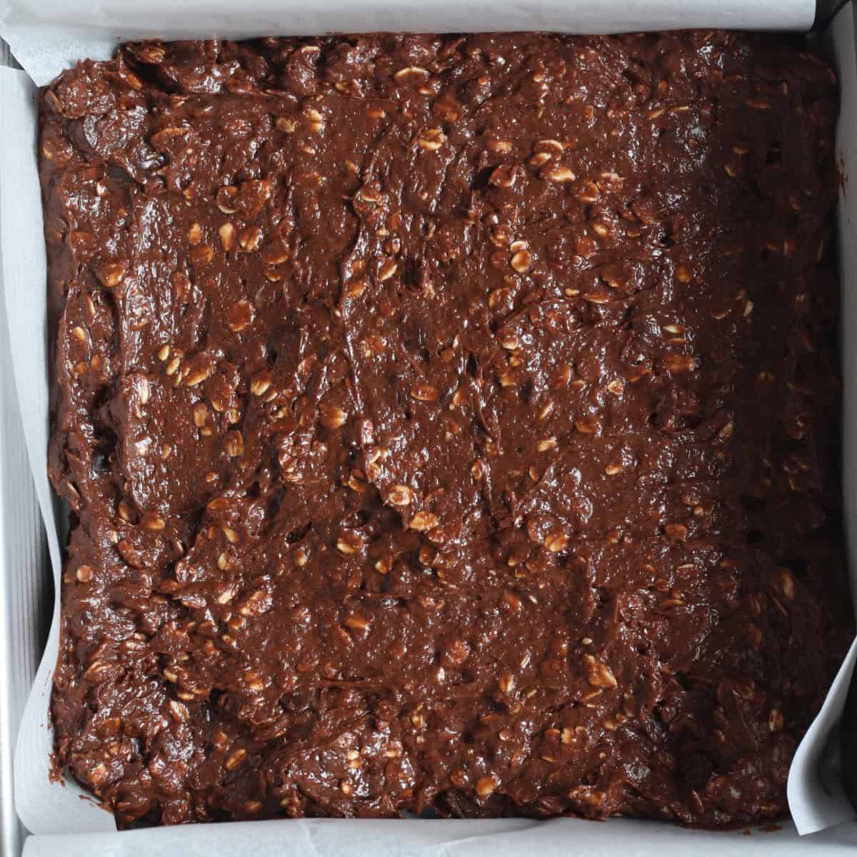 spreading the brownie batter across the baking pan evenly