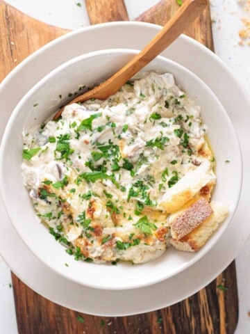 Creamy Mushroom Dip - white bowl with a wooden spoon and toasted bread on side.