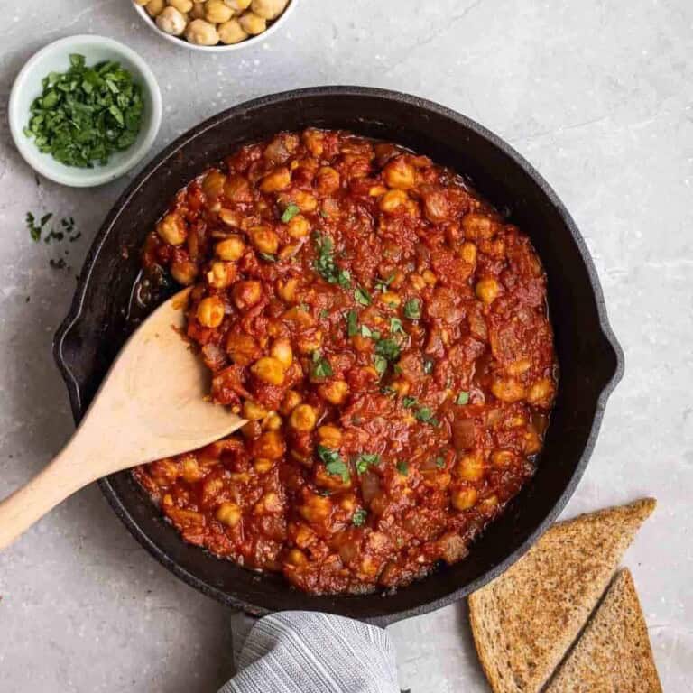 Hearty pan-fried chickpeas in tomato sauce, garnished with herbs and served with toasted bread.