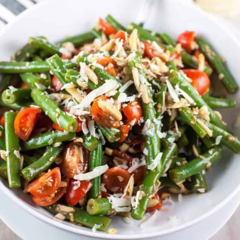 Italian green bean salad with cherry tomatoes and sliced almonds in a white bowl
