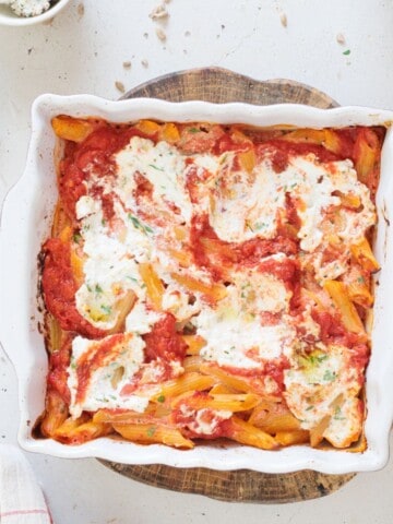 close up image of vegan baked ziti served in a casserole baking pan garnished with parsley on top - feature image