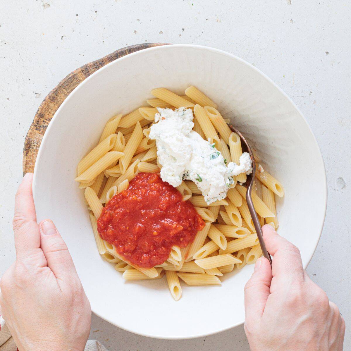 process - making the ziti: Adding basil, black pepper and garlic powder sunflower seed ricotta mix in a mixing bowl along with the pasta