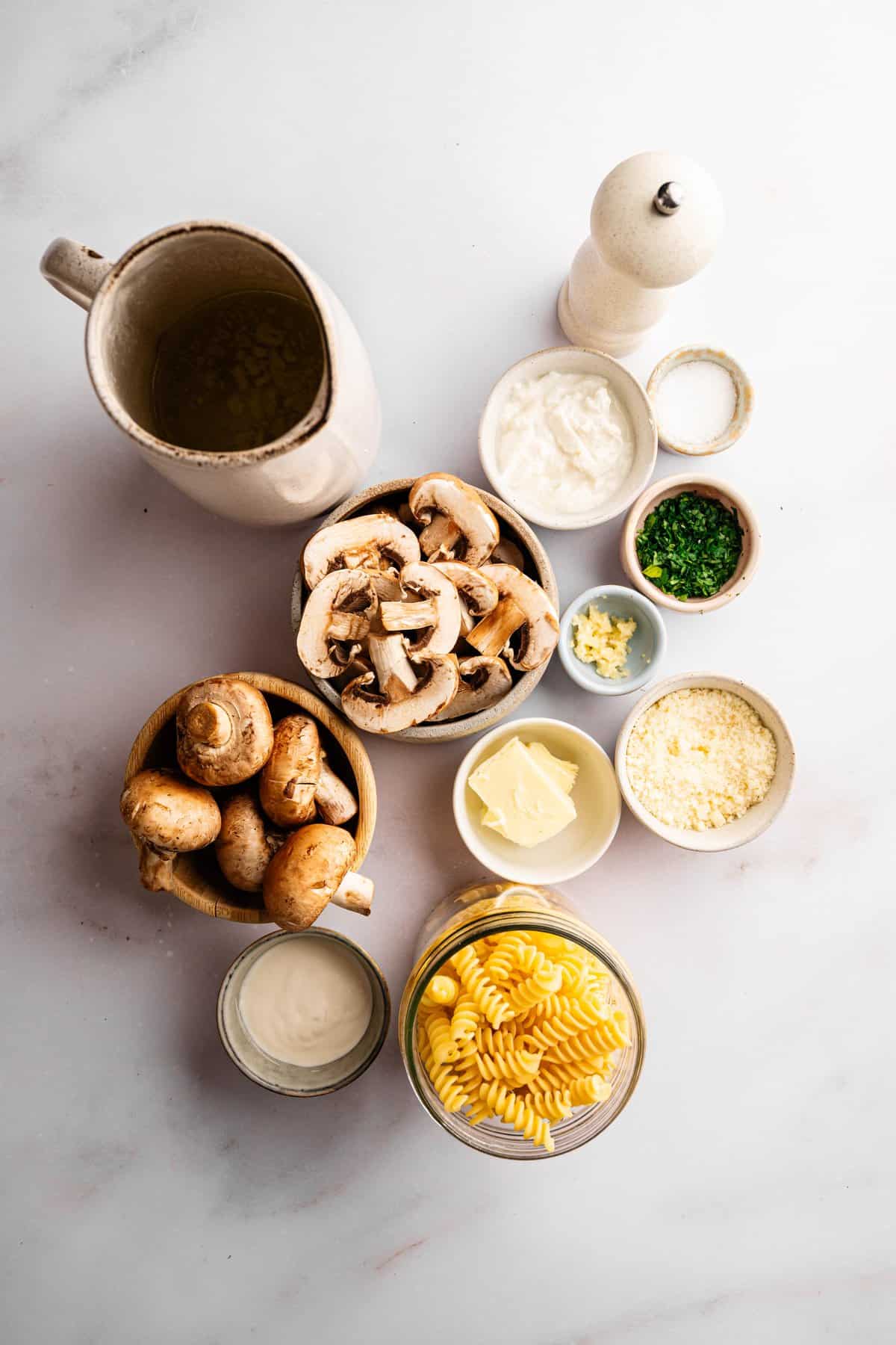 Ingredients for mushroom ricotta pasta including portobello mushrooms, fusilli, ricotta cheese, Parmesan, garlic, butter, heavy cream, and vegetable broth