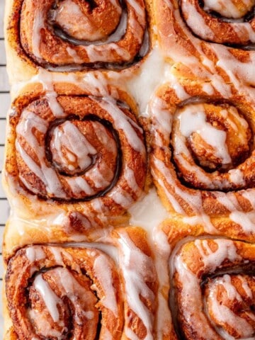 Vegan Cinnamon Rolls on a cooling wire rack topped with vanilla glaze