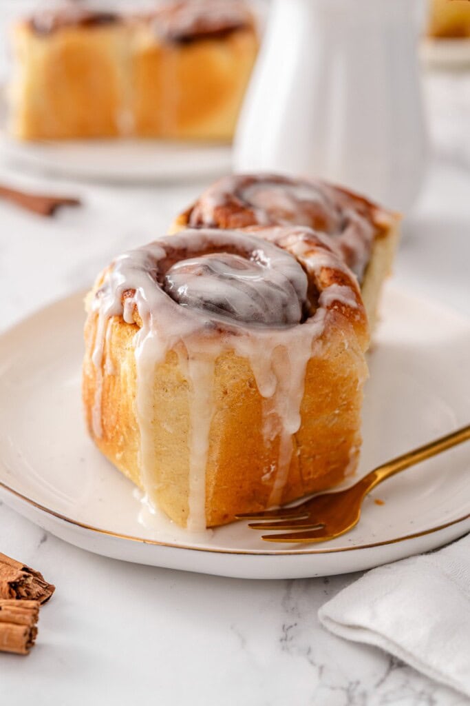 vegan-cinnamon-rolls-plated-with-gold-fork-and-cinnamon-sticks
