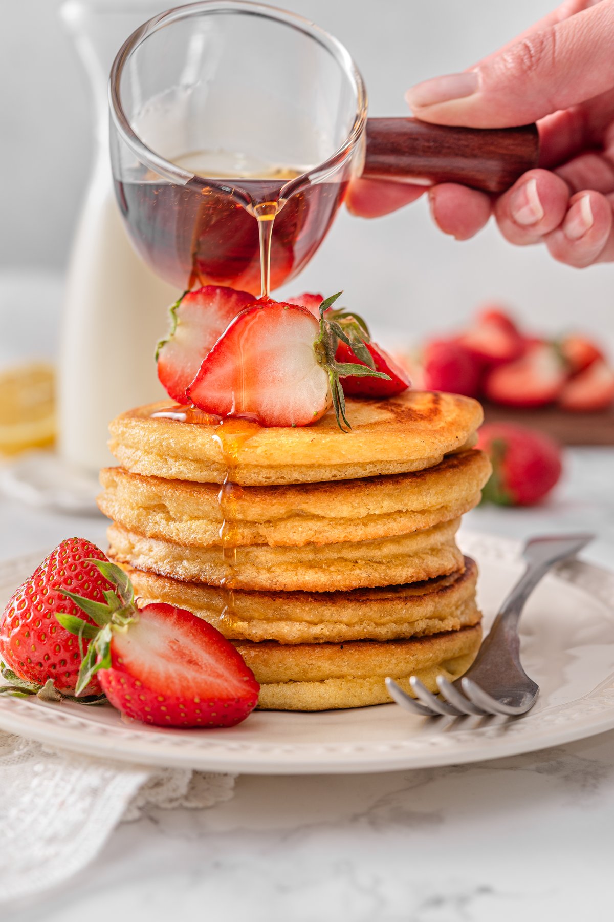 Overhead view of chickpea flour pancakes on a plate with maple syrup being drizzled on top