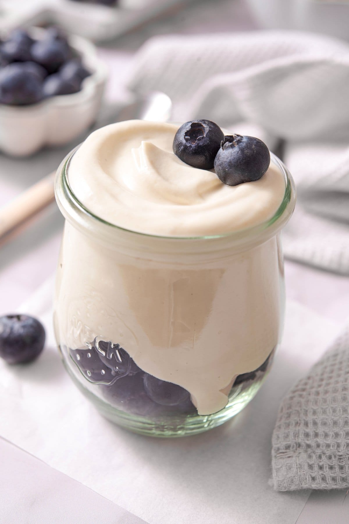Cashew whipped cream in a glass jar topped with fresh blueberries, showing the smooth and dense texture.