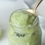 Creamy green protein smoothie in a glass jar with a spoon full of smoothie out of the jar