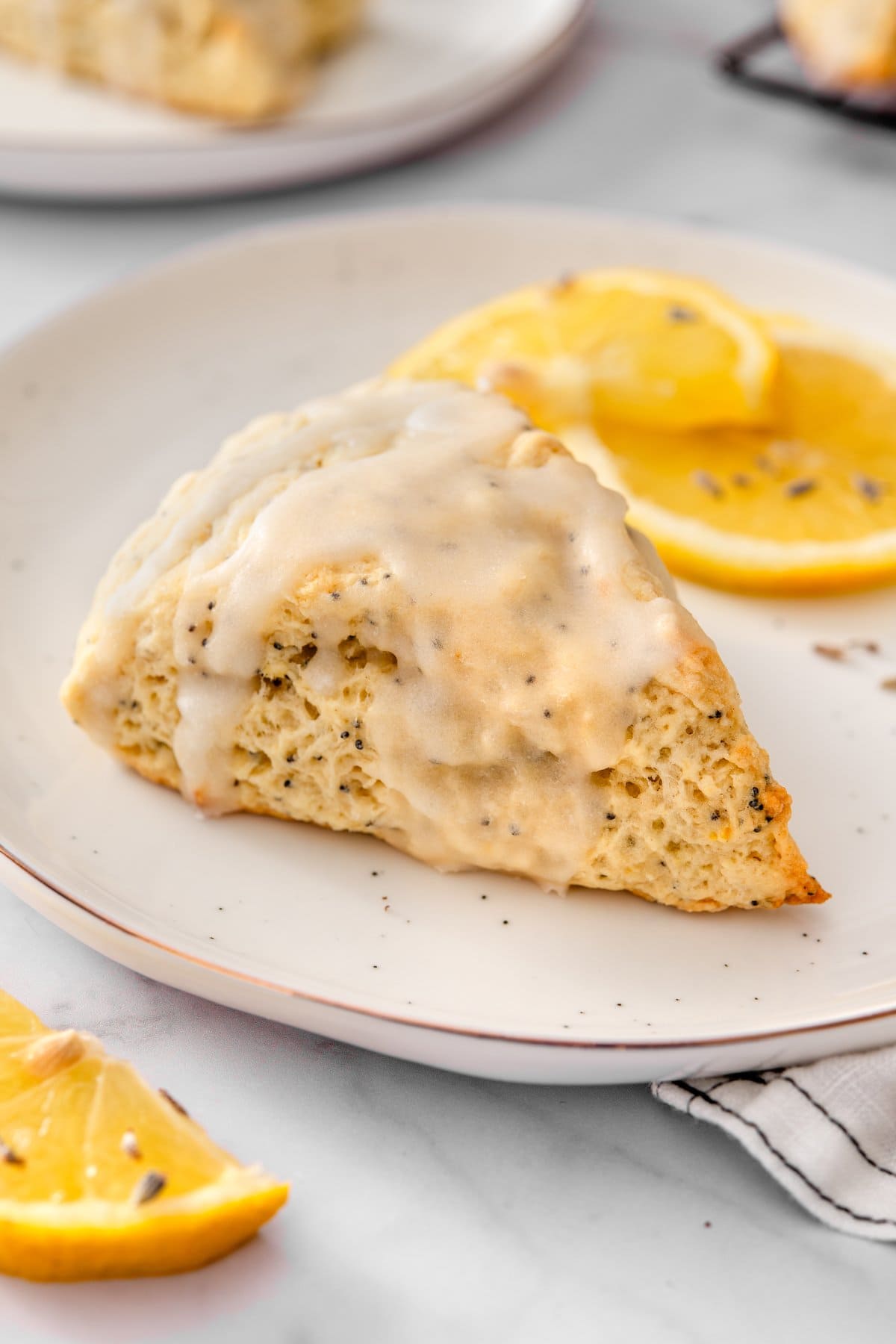 1 vegan lemon poppy seed scone on a small plate sprinkled with lavender icing