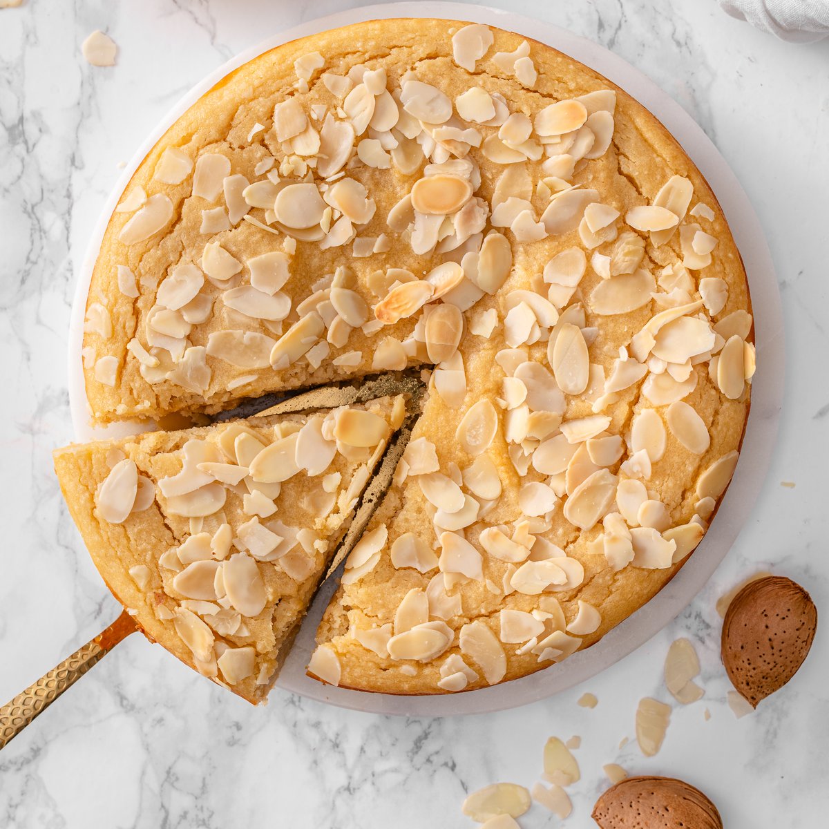 Almond ricotta cake topped with sliced almonds on a serving plate