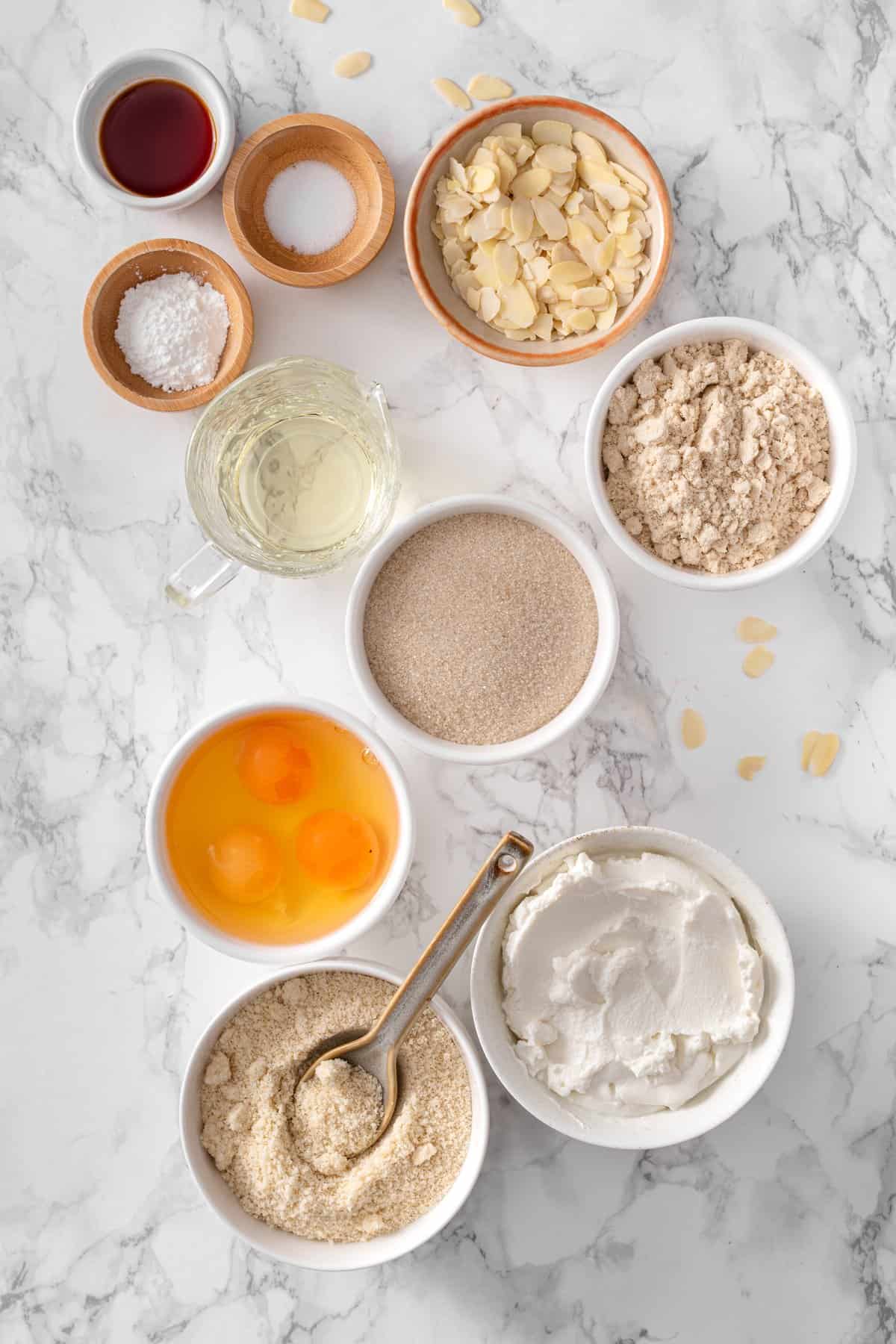 Key ingredients to make almond ricotta cake including almond flour, almond meal, eggs, ricotta, oil, sliced almonds