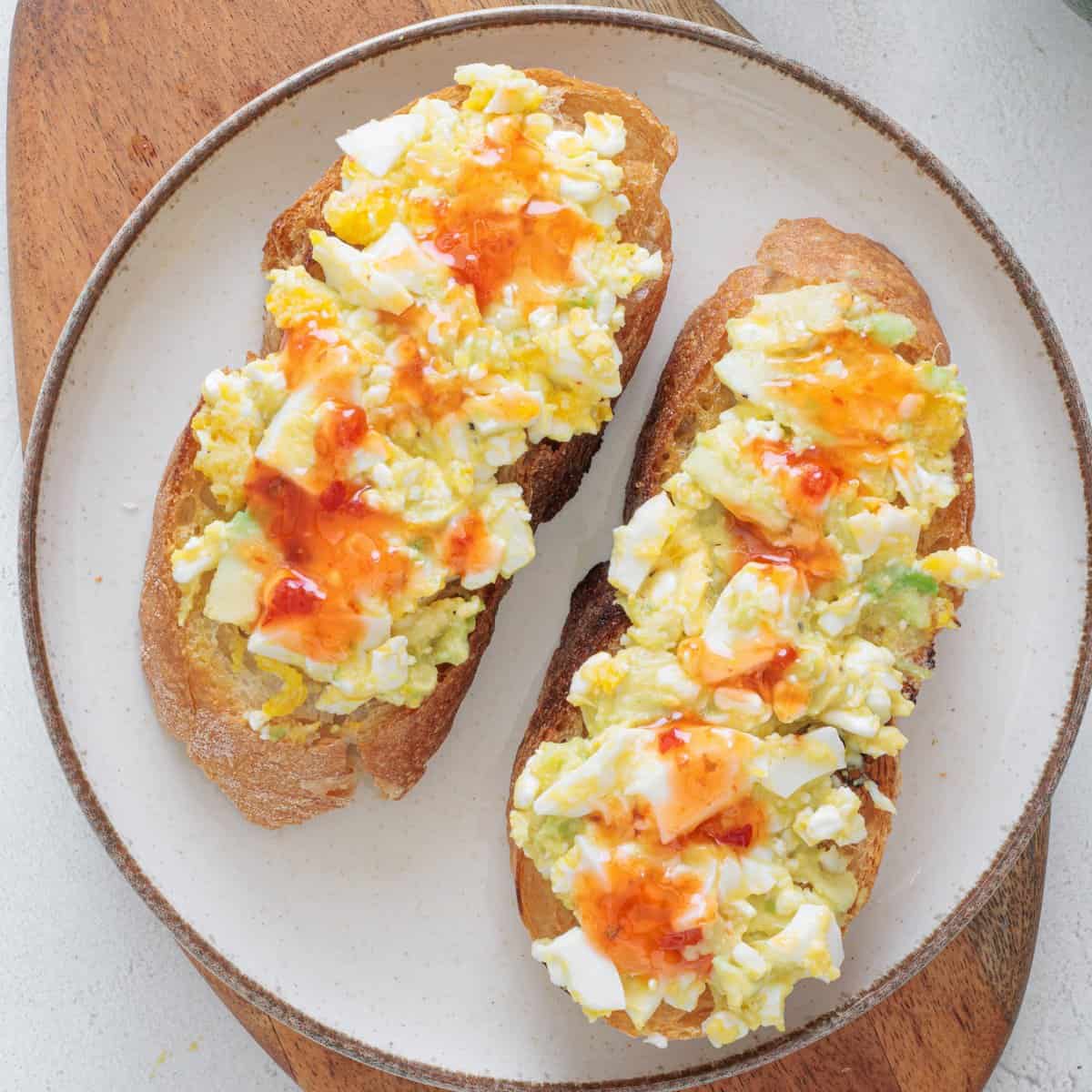 Avocado Cottage Cheese Toast on a white plate drizzled with hot sauce
