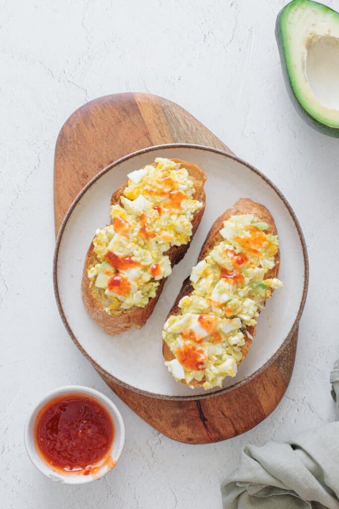 Avocado Cottage Cheese Toast on a white plate with hot sauce on the side