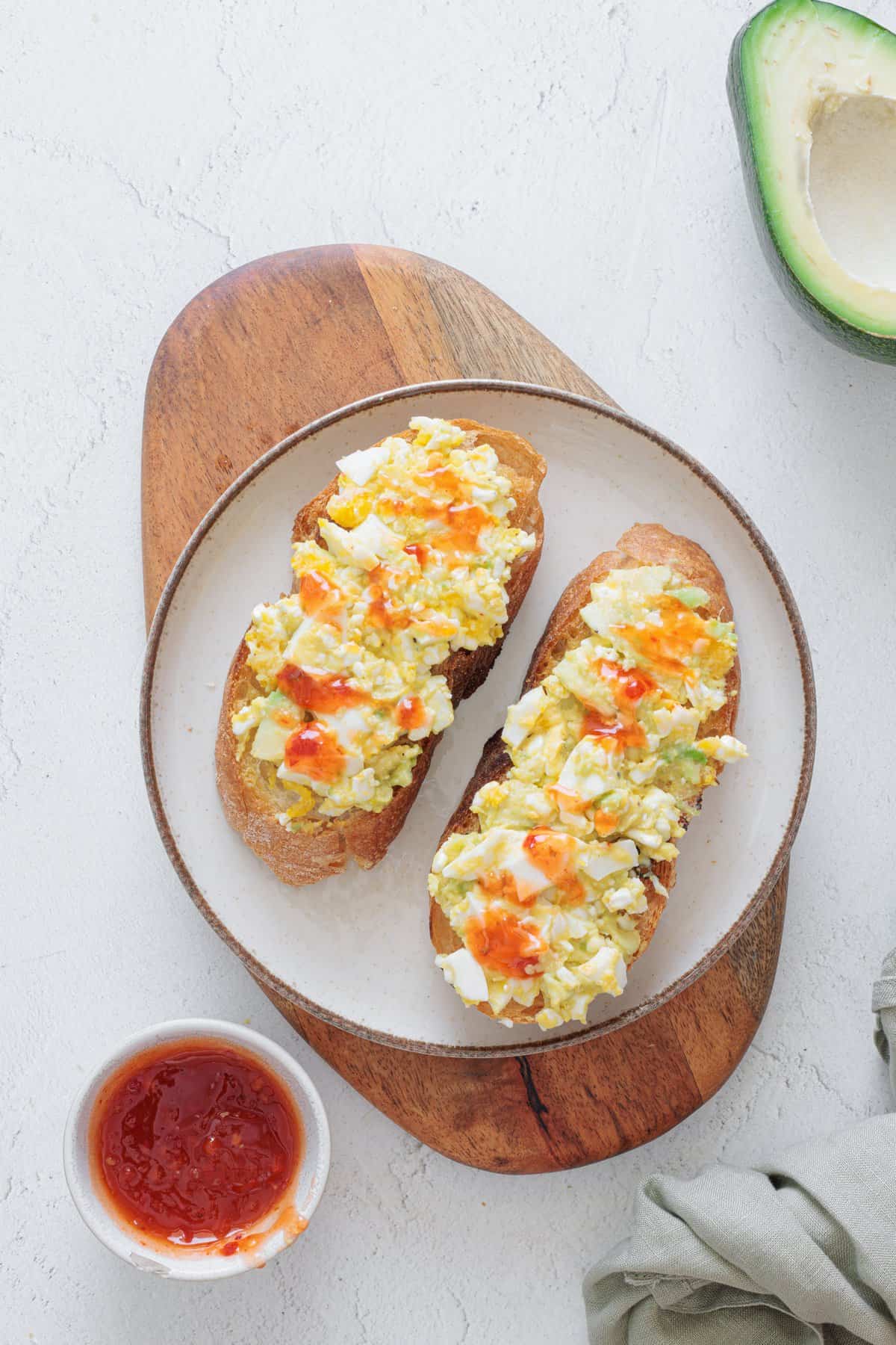 Avocado Cottage Cheese Toast on a white plate with hot sauce on the side