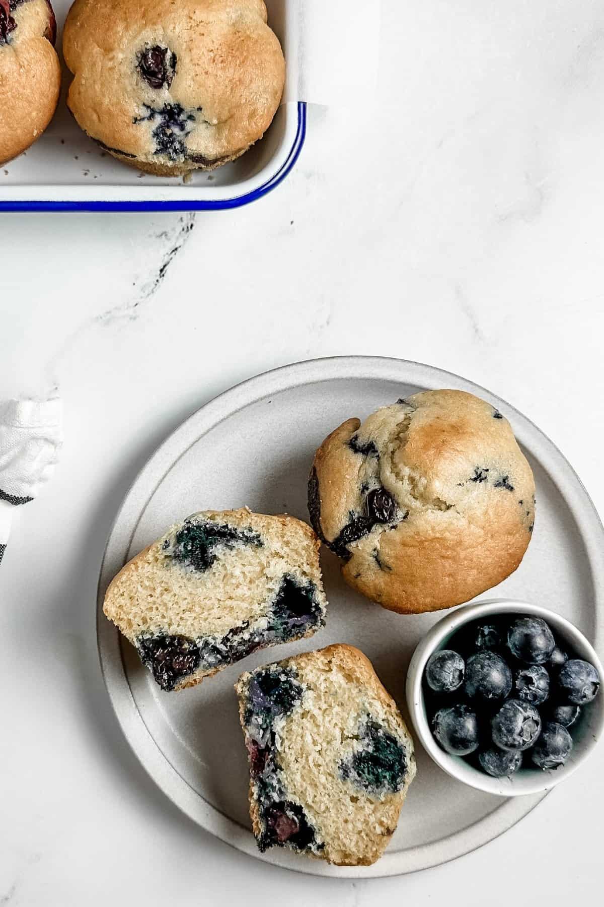 Dairy free blueberry muffins served with blueberries on a white plate