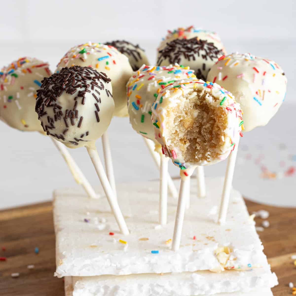 The vegan cakes are popped on Styrofoam sticks, coated in vegan white chocolate and vegan dark chocolate, and topped with sprinkles.