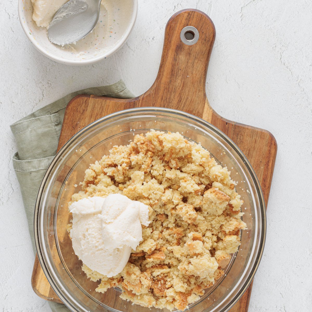 Place the crumbled vegan cake and vegan frosting in a glass bowl on a wooden board, ready to mix for cake pops.