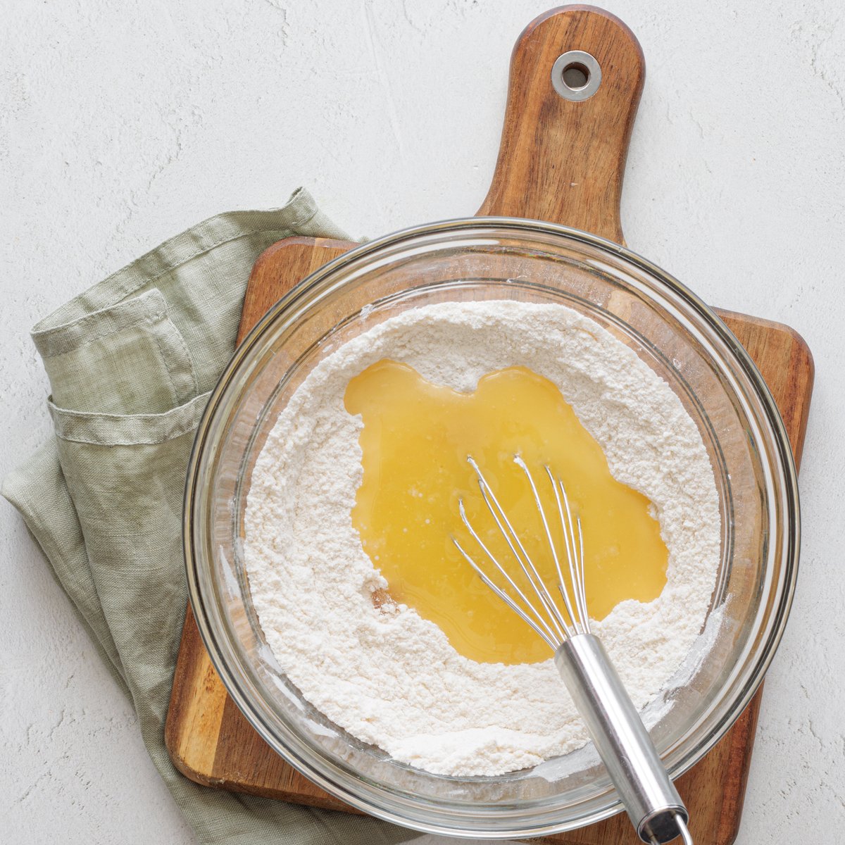 Whisk all-purpose flour and melted vegan butter in a glass bowl on a wooden cutting board for vegan cake pops.