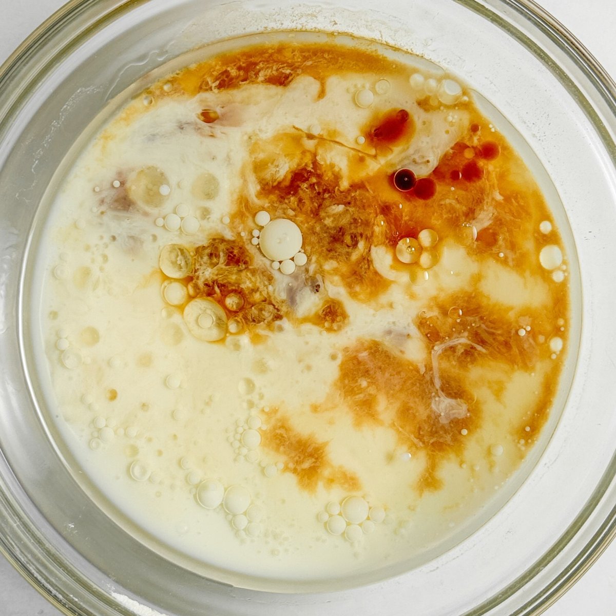 Milk and sugar mixture with bubbles in a glass bowl for chocolate loaf cake batter preparation