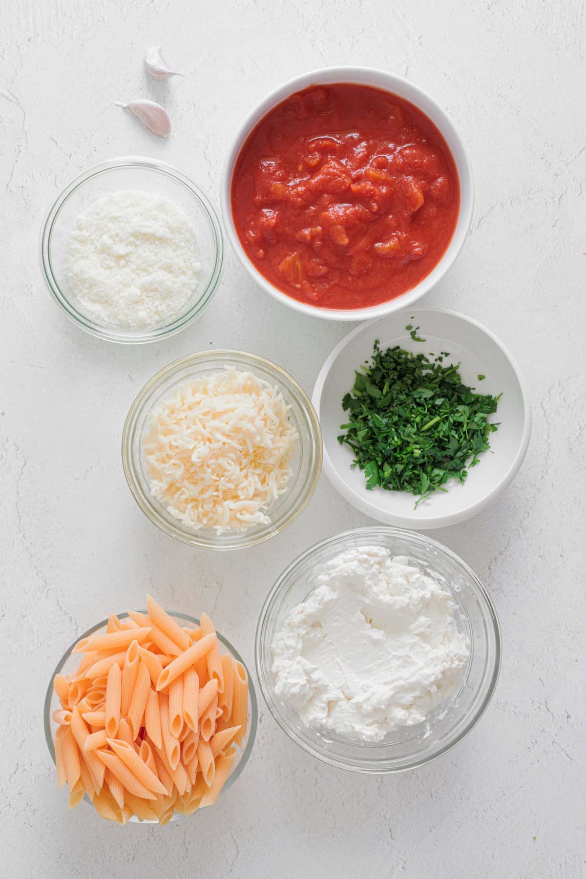 Ingredients for Easy Cheesy Red Lentil Baked Ziti: red lentil penne, crushed tomatoes, ricotta, shredded mozzarella, parmesan, fresh parsley, and