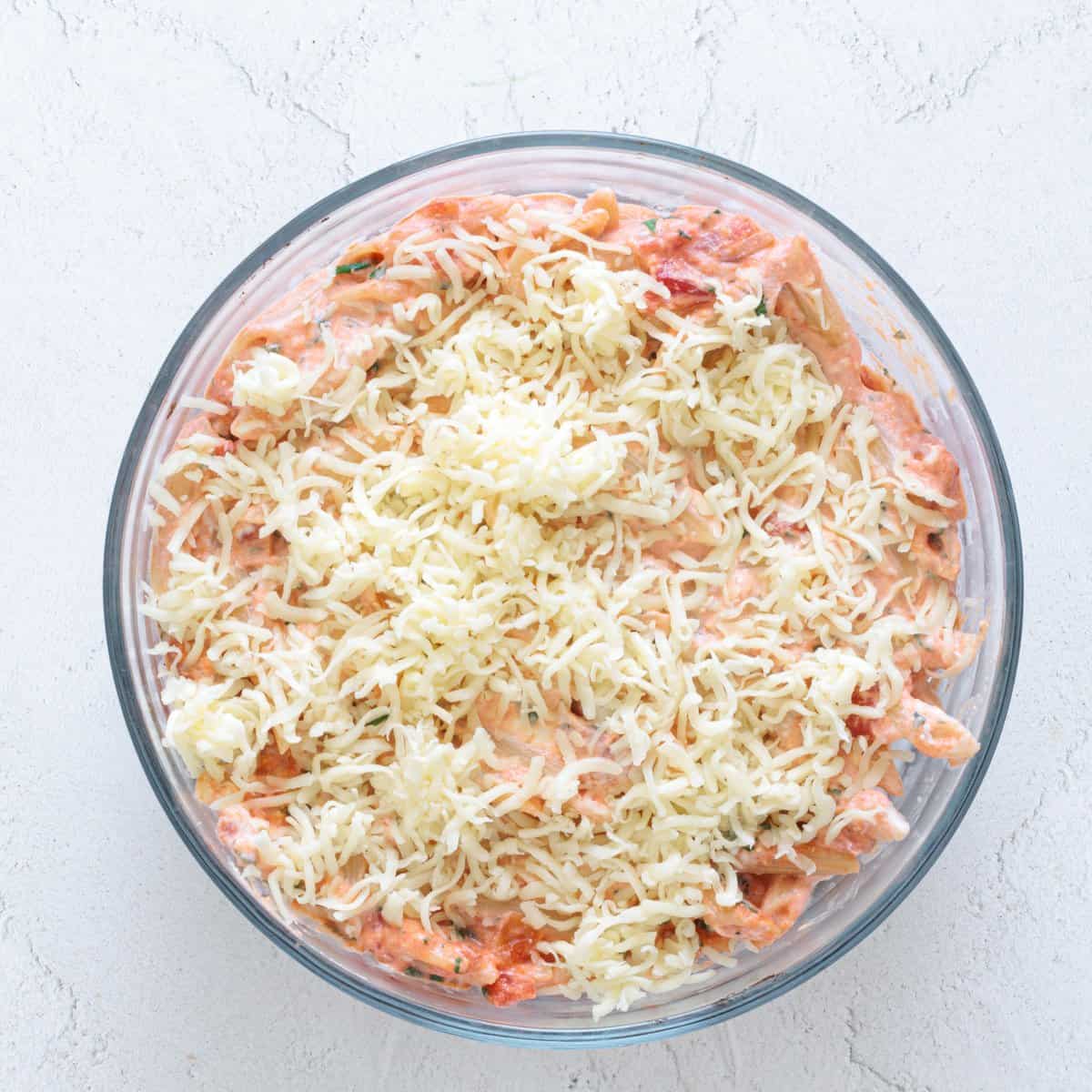 Glass baking dish filled with red lentil baked ziti in creamy tomato sauce topped with shredded mozzarella cheese