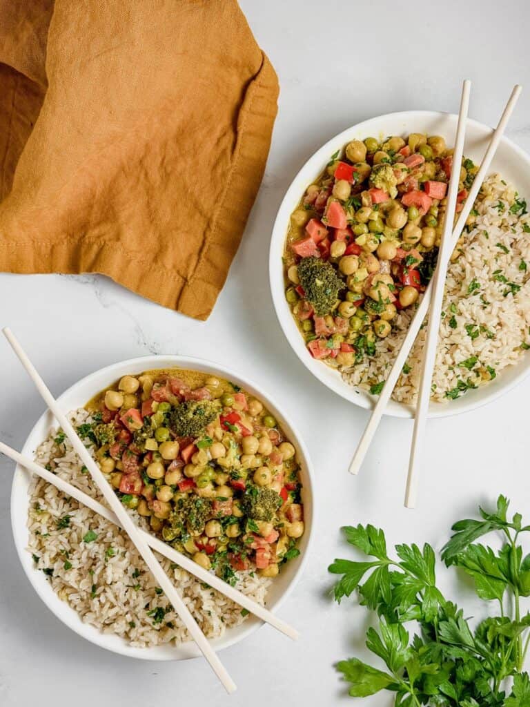 two bowls of vegan chickpea curry with chopsticks on top of each bowl.