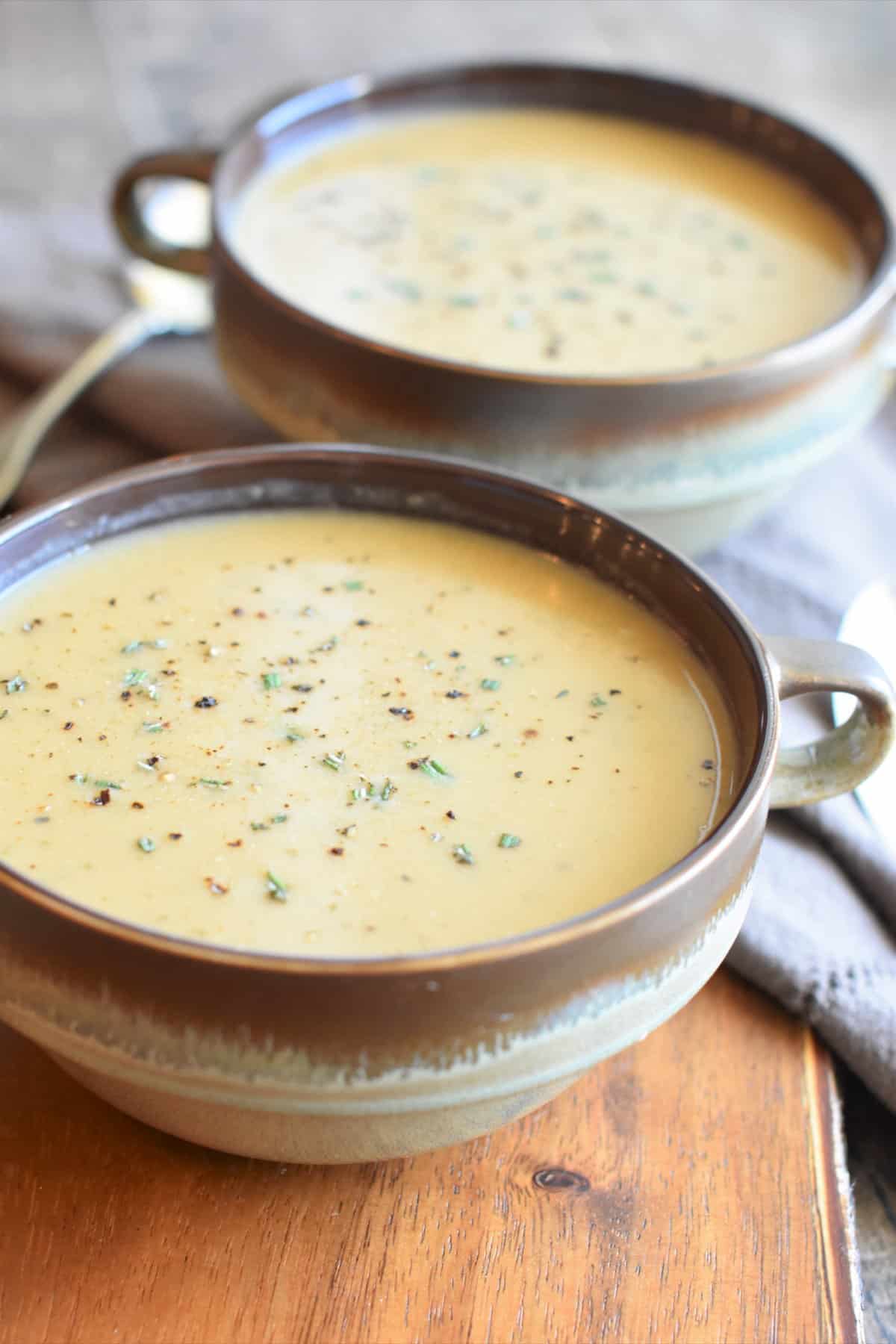 front view of soup in two rustic bowls with spoons next to them