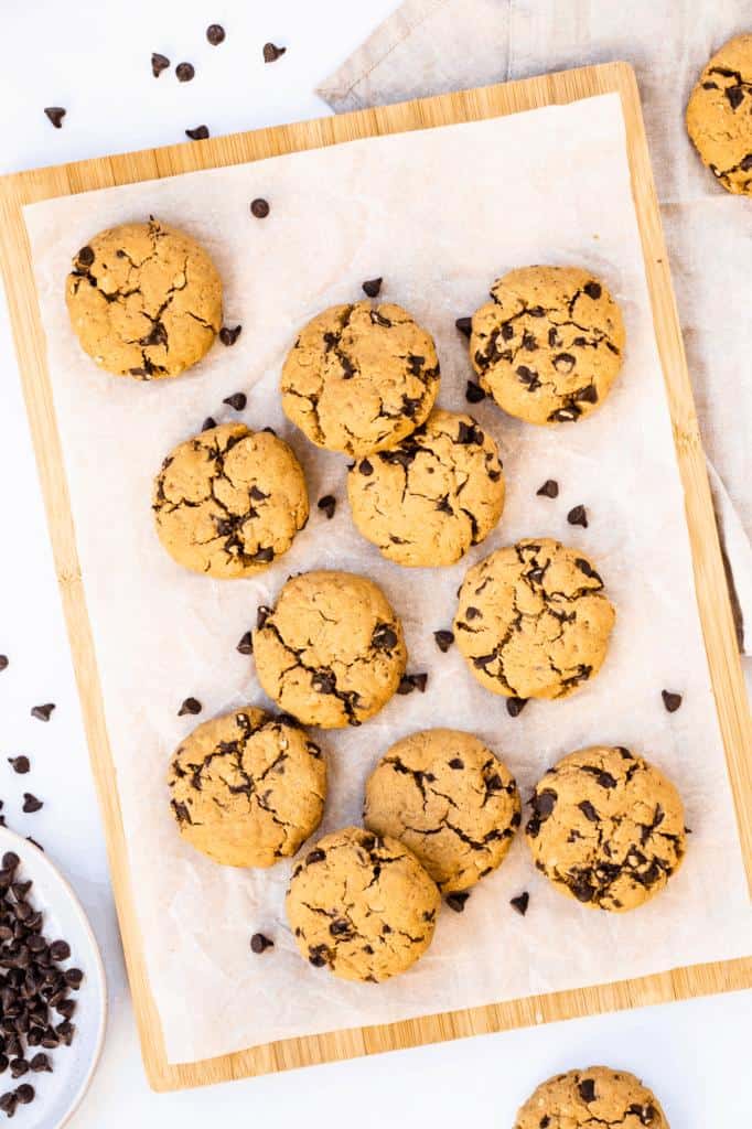 overhead view of vegan peanut butter oatmeal chocolate chip cookies on parchment paper with scattered chocolate chips