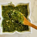 close up of a wooden spoon full of basil chimichurri sauce