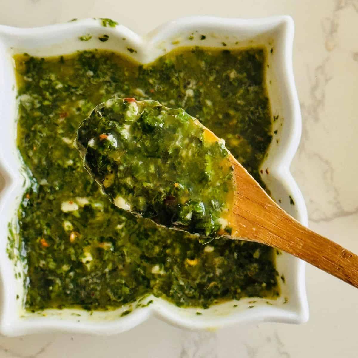 close up of a wooden spoon full of basil chimichurri sauce