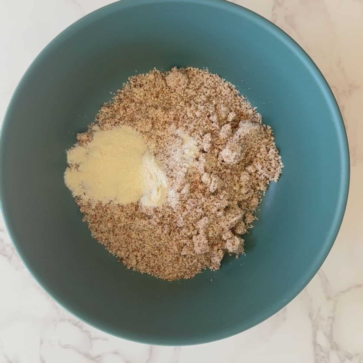 Almond flour and vanilla protein powder combined in a teal bowl, first step for Pumpkin Spice Protein Balls.