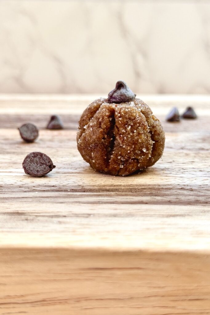 single view of a pumpkin protein ball with chocolate chips scattered across the wooden board.