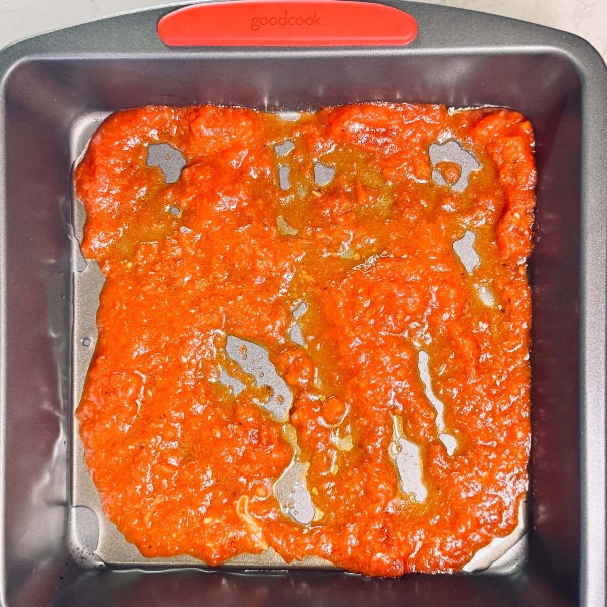 Marinara sauce spread in a square GoodCook baking pan as the first layer for Spinach Ricotta Lasagna.
